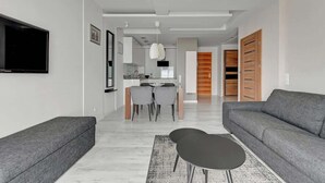 Ein modernes Wohnzimmer mit einem grauen Sofa, einem schwarzen Couchtisch und einem flachbildfernseher an der Wand.
