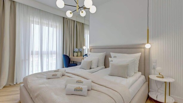 Ett hotellrum med en stor säng, ett skrivbord och en stol. Det finns två kuddar med hotellets namn på.