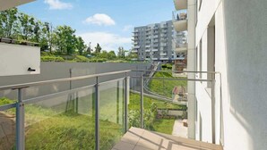 En moderne lejlighedskompleks med glasbalconer, en græsplædehave og frit udsyn til det omkringliggende område.