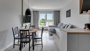 Een modern appartement met een eethoek, een bank, een keukeneiland en een groot raam met uitzicht.