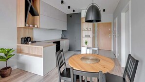 Een moderne keuken met een centraal eiland, een eetgedeelte met een ronde tafel, en een gang naar een deur.