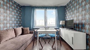 Un salon comprenant un canapé, une table à manger avec des chaises, un téléviseur et un meuble.