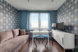 Ein Wohnzimmer mit Sofa, einem Esstisch mit Stühlen, einem Fernseher und einem Schrank.