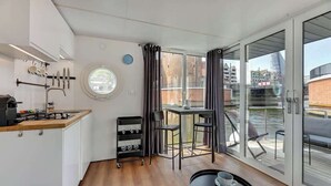 A modern kitchen with a coffee machine, a wine rack, and a dining area with a table and chairs.