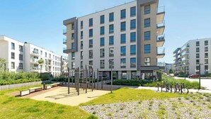 Ein modernes Mehrfamilienhaus mit Balkonen, einem Spielplatz und abgestellten Fahrrädern.