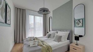 Quarto moderno com cama, mesa de cabeceira e um espelho grande.