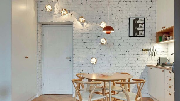 A kitchen with a white brick wall, wooden furniture, pendant lighting, and a framed picture. - Ogarna's Bells | Main Old Town | Perfect Stay (Gdańsk)
