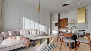 Ein modernes Wohnzimmer mit Sofa, Esstisch, Stühlen und einer Küchenzeile mit Schränken und Arbeitsplatte.