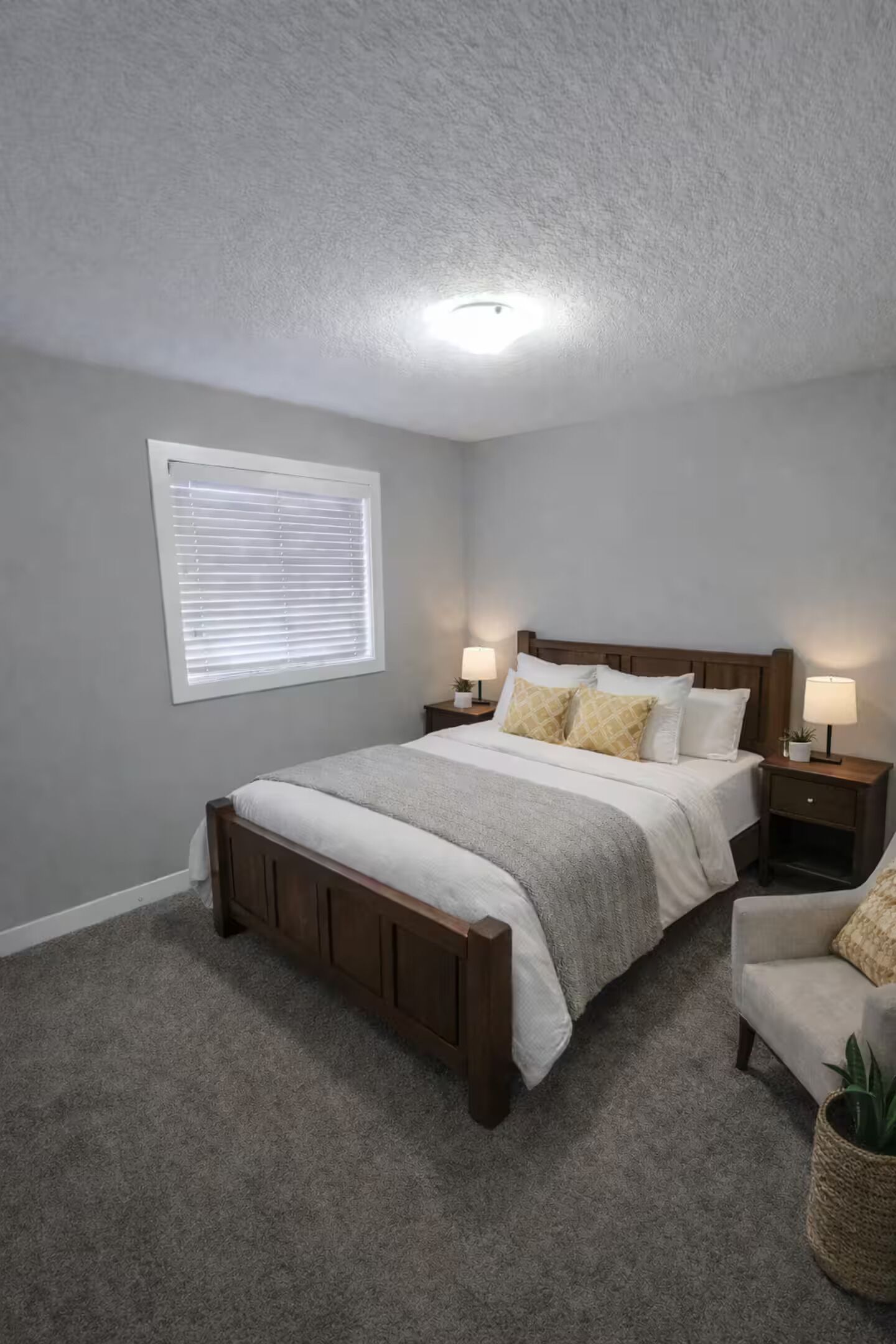 Une chambre à coucher avec un lit, des tables de chevet, une fenêtre et une petite table de nuit avec une lampe.