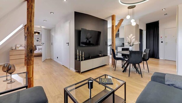 A modern living room with a TV, dining area, and a glass coffee table. - Grunwaldzka Attic | Great Location | Family Stay (Gdańsk)