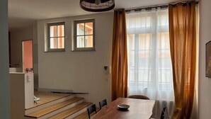 A dining area with a table and chairs, a staircase, and a window with curtains. - Roof terrace apartment in Avignon (Avignon)