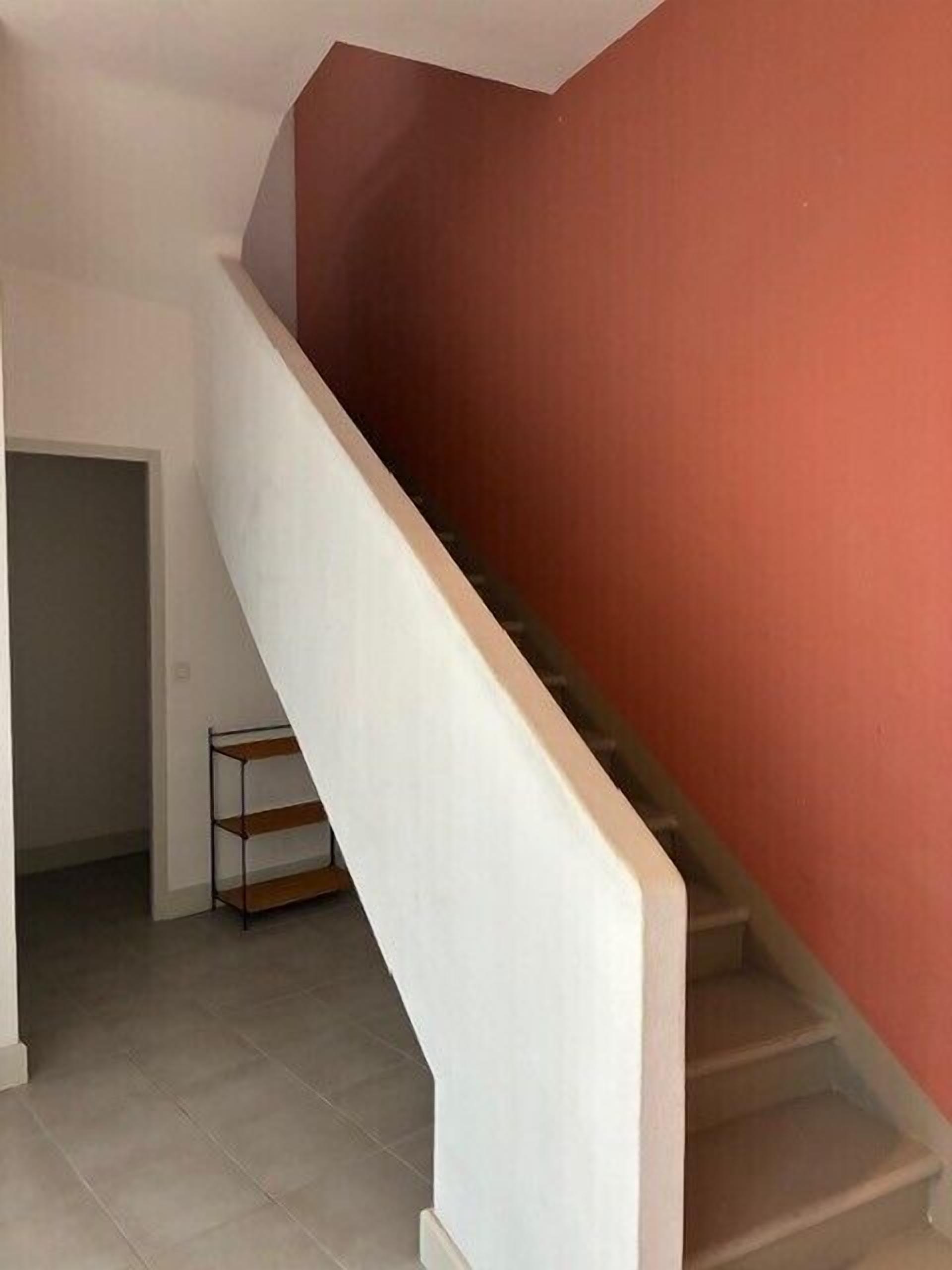 Un escalier avec une rampe blanche et un mur rouge.