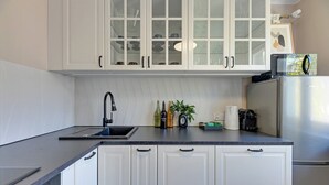 Eine Küche mit weißen Schränken, einer schwarzen Arbeitsplatte, einem Edelstahlkühlschrank und einer Mikrowelle.