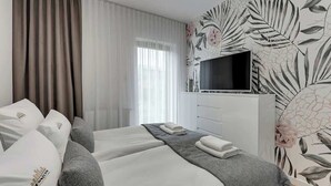 Ein Hotelzimmer mit einem Bett, einem Fernseher, einem Schminktisch und blumigem Wandpapier.