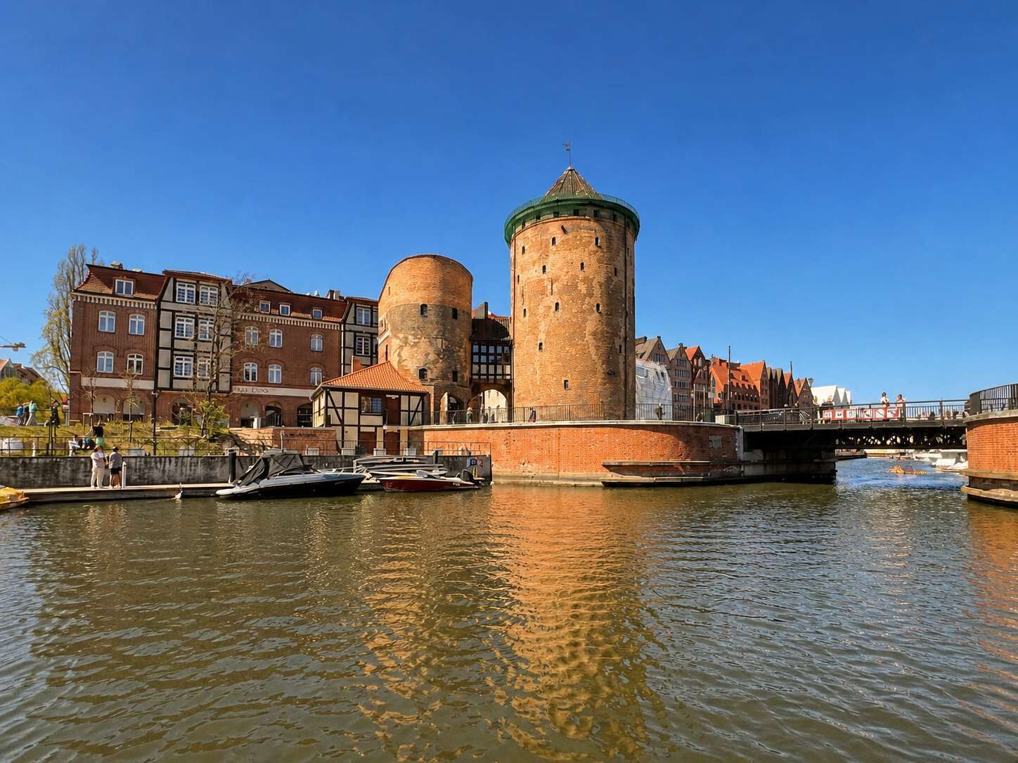 A historic tower with a round base and a dome, surrounded by traditional buildings and a canal.