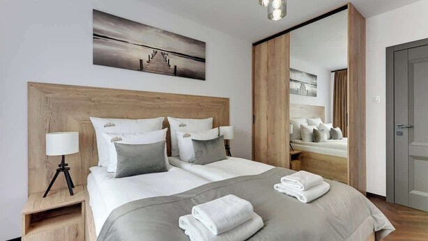 Een hotelkamer met een groot bed, twee nachtkastjes met lampen, een spiegel en een schilderij aan de muur.