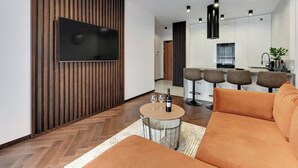 Een moderne woonkamer met een flatscreen televisie, een ronde salontafel en een bank.
