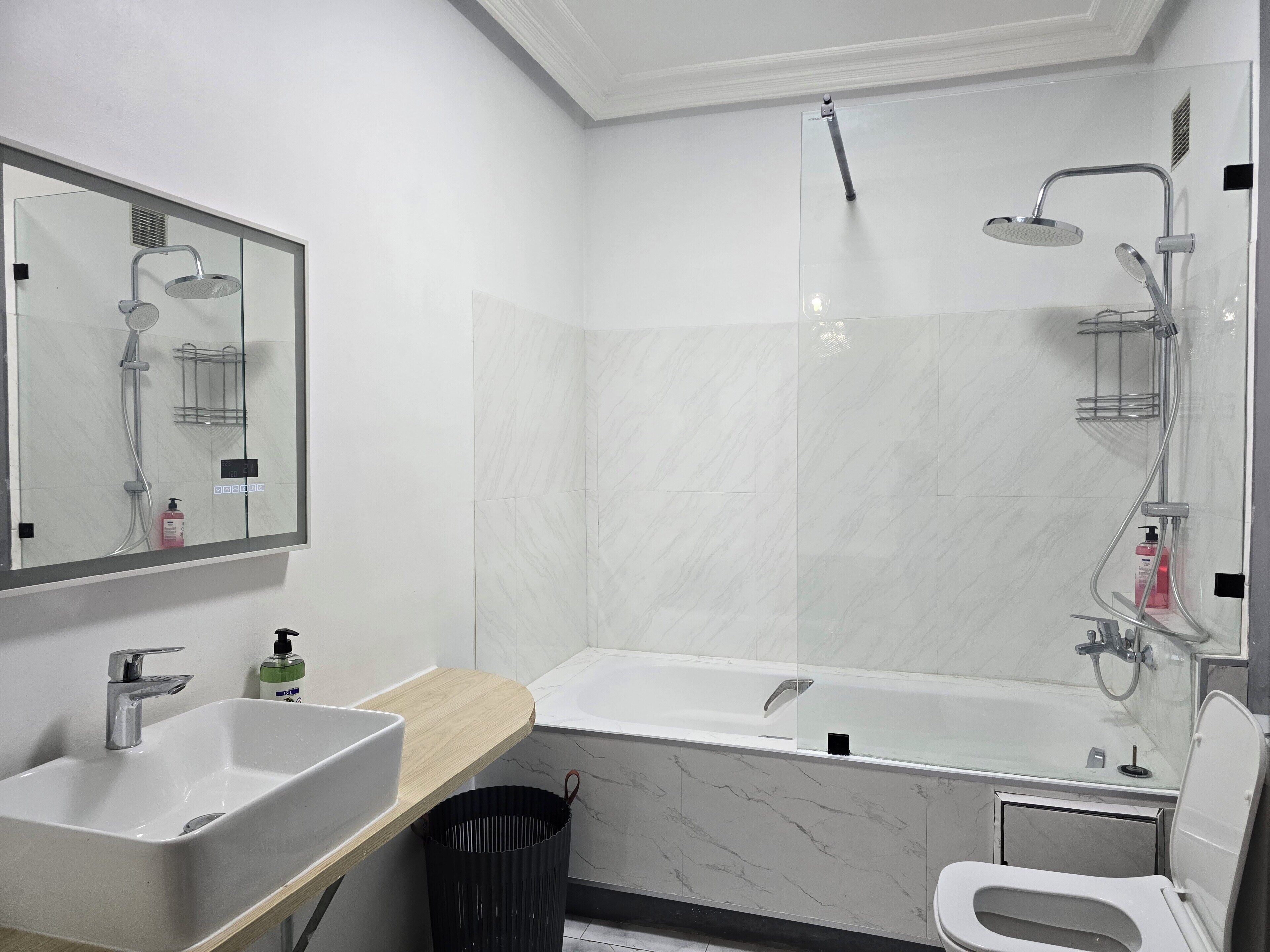 Un bagno moderno con lavandino, specchio, doccia e servizi igienici.