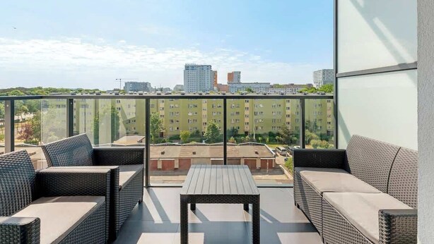 En balkon med fletmøbler, et bord og udsigt over byen.