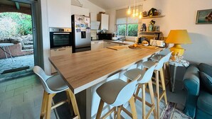 Una cocina moderna con una isla central, taburetes de bar, una mesa de comedor y un sofá.