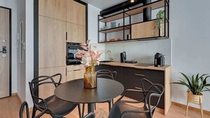 Een moderne keuken met houten kastjes, een zwart aanrecht en een eethoek met een ronde tafel en stoelen.