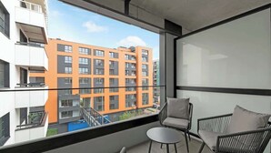 A balcony with a view of a modern building, a small table, and two chairs.