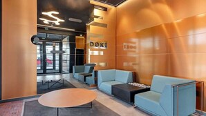 A modern lobby with a reception desk, seating area, and a large wall-mounted sign. - Doki A34 B | Gdańsk Shipyard & Foodhall (Gdańsk)