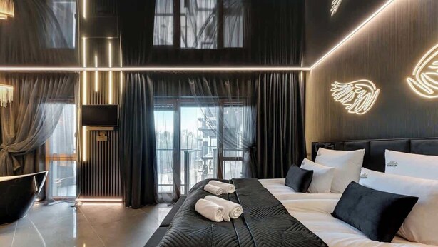 Une chambre d’hôtel moderne dotée d’un grand lit, d’un téléviseur à écran plat et offrant une vue sur la ville grâce à de grandes fenêtres.