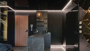 Un intérieur moderne avec une porte en bois, un mur d’accent en marbre, un globe terrestre et un escalier doté d’une rampe.