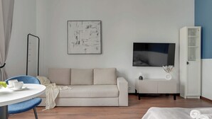 A modern living room with a sofa, a TV, a white cabinet, and a round table with cups. - Chopina Studio | 300 metres to the Sopot beach (Sopot)