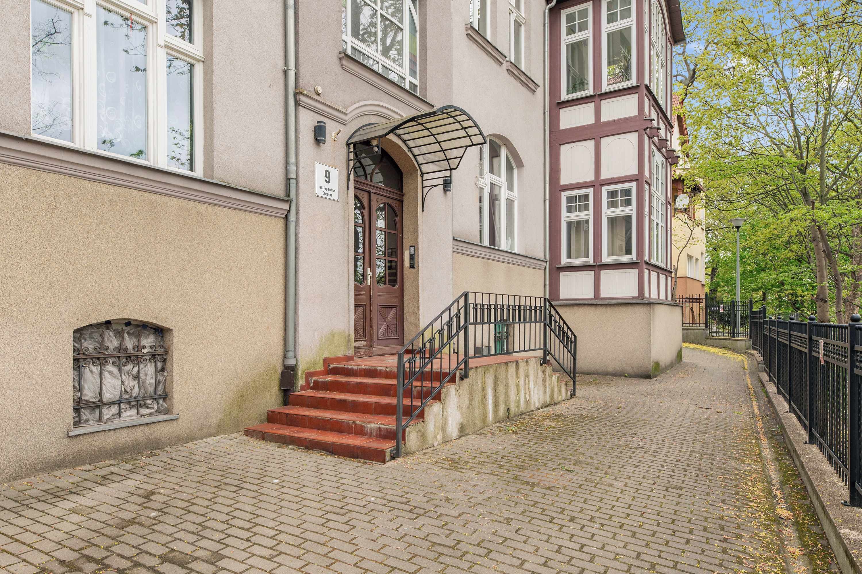 A building with a stone facade, a wooden door, and a staircase leading to the entrance.