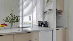 A modern kitchen with a built-in stove, a sink, and a window with blinds. - Chopina Studio | 300 metres to the Sopot beach (Sopot)