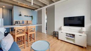 Un soggiorno moderno con cucina, zona pranzo e TV.