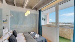 Una camera da letto moderna con un letto grande, vista sulla città e un balcone.