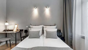 Ein ordentlich eingerichtetes Schlafzimmer mit Bett, Nachttischen, Schreibtisch und Stuhl.