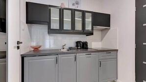 Una cocina con gabinetes grises, una campana extractora negra y una cafetera.