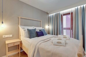 Ein ordentlich bezogenes Bett mit Kopfteil, Nachttisch und einem Vorhangfenster.