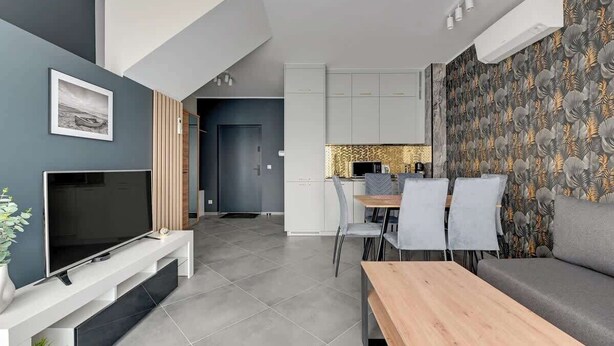 Ein modernes Wohnzimmer mit Fernseher, Sofa und Essbereich.