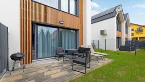 Ein modernes Haus mit Terrasse, Sitzgelegenheit im Freien und Grill.