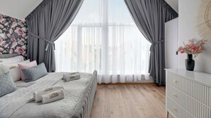 Ein Schlafzimmer mit Bett, Vorhängen, einem Schminktisch und einem Fenster mit Blick.