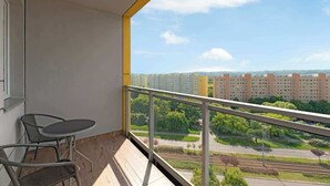 En balkong med utsikt över stadsbilden, ett bord och två stolar.