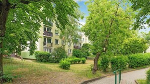 A residential building with multiple balconies, surrounded by lush greenery and a paved pathway. - Chłopska 2 | Near the Beach (Gdańsk)