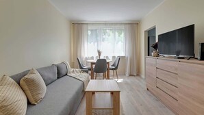 A modern living room with a sofa, a small table, a TV, and a dining area. - Chłopska 2 | Near the Beach (Gdańsk)