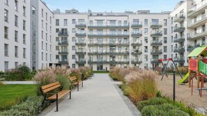 En flervåningsbostadsbyggnad med en central gångväg, bänkar och en lekplats.