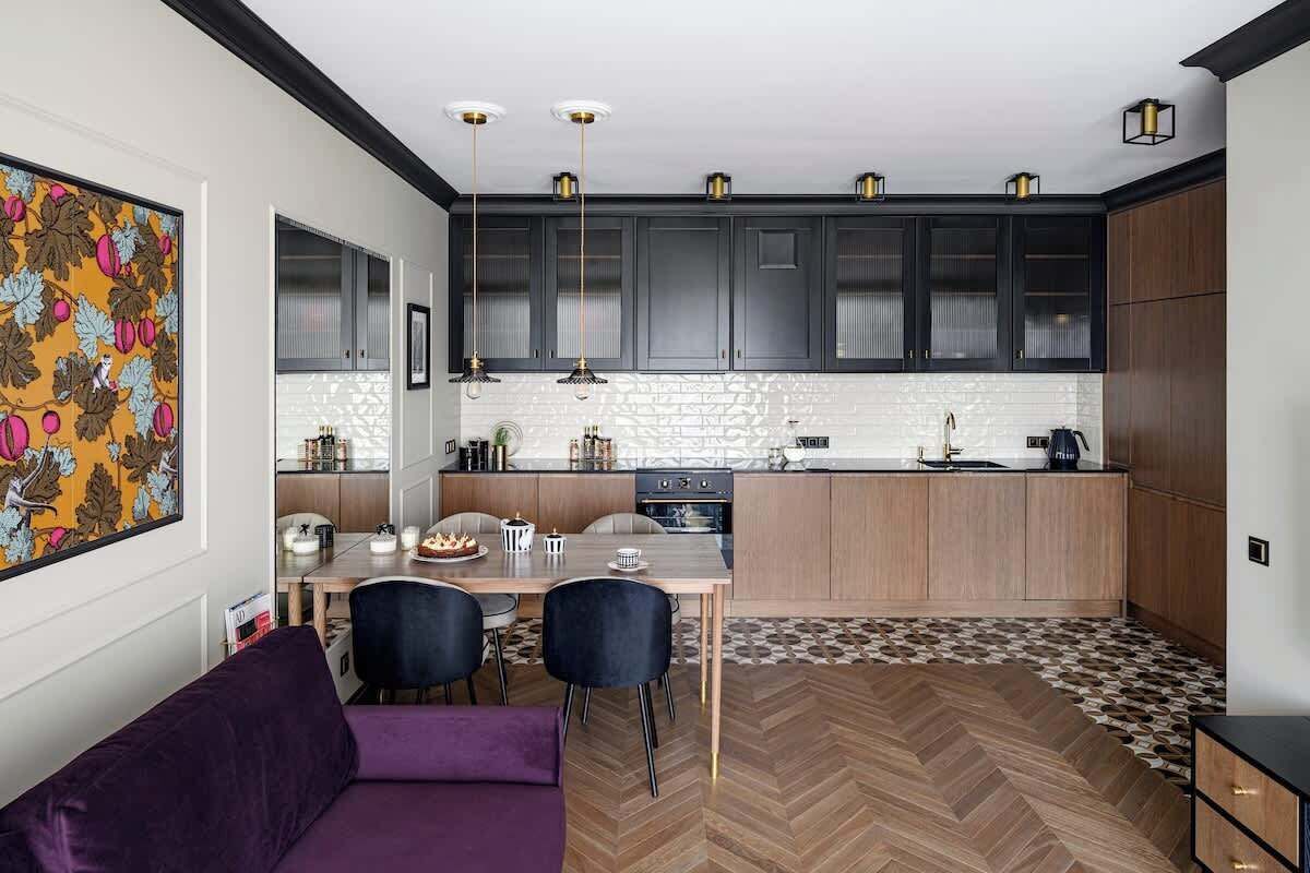 Une cuisine moderne avec des meubles de couleur sombre, un parquet à motifs en chevrons et des luminaires suspendus.