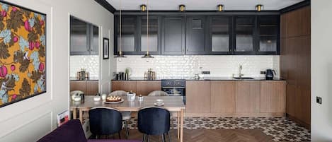 A modern kitchen with dark cabinets, a herringbone-patterned floor, and pendant lighting.