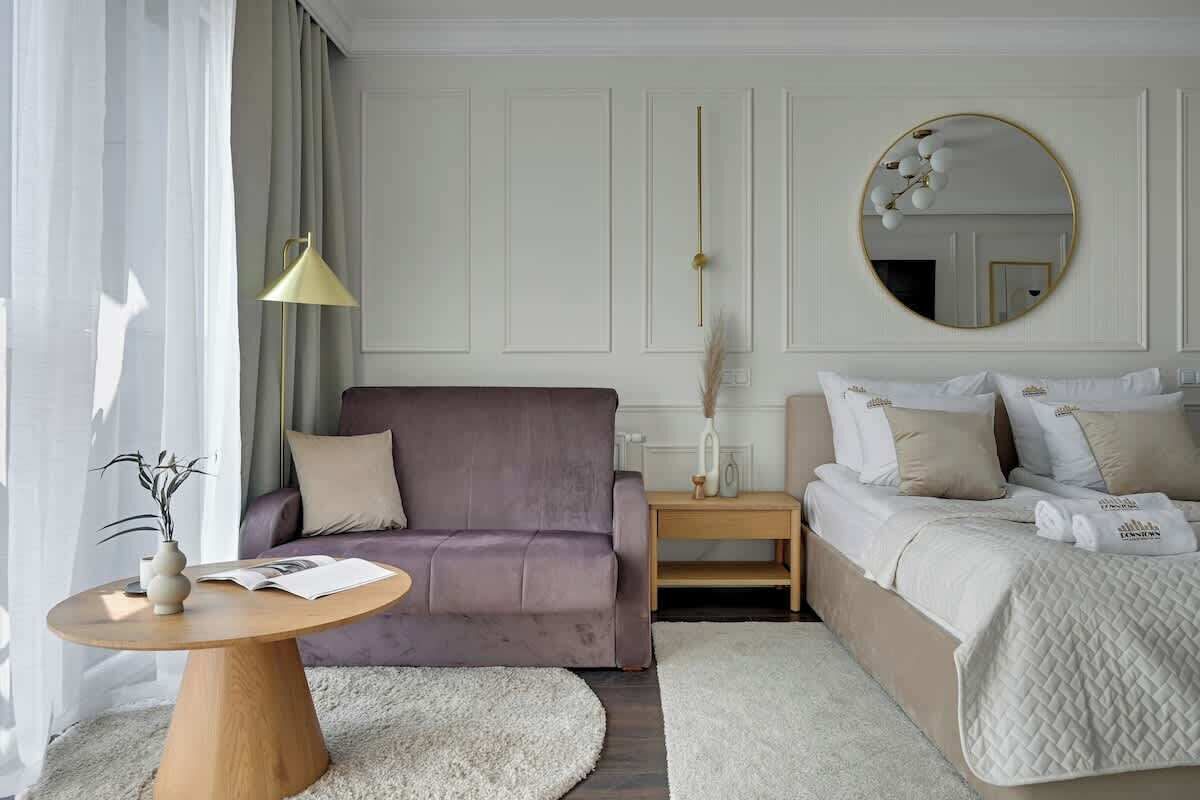 Ein modernes Schlafzimmer mit einer Couch, einem runden Couchtisch, einem Bett und einem runden Spiegel.