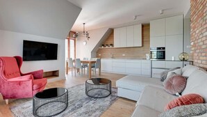 Een moderne woonkamer met een rode stoel, een witte bank en een eethoek met een tafel en stoelen.