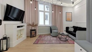 A modern living room with a flat-screen TV, a sofa, a chair, a small side table, and a decorative rug. - 500 metres to the Sopot Beach | Monte Cassino (Sopot)