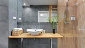 A modern bathroom with a vessel sink, a shower, and a wooden vanity. - Aura 196B | Riverside | City Center (Gdańsk)